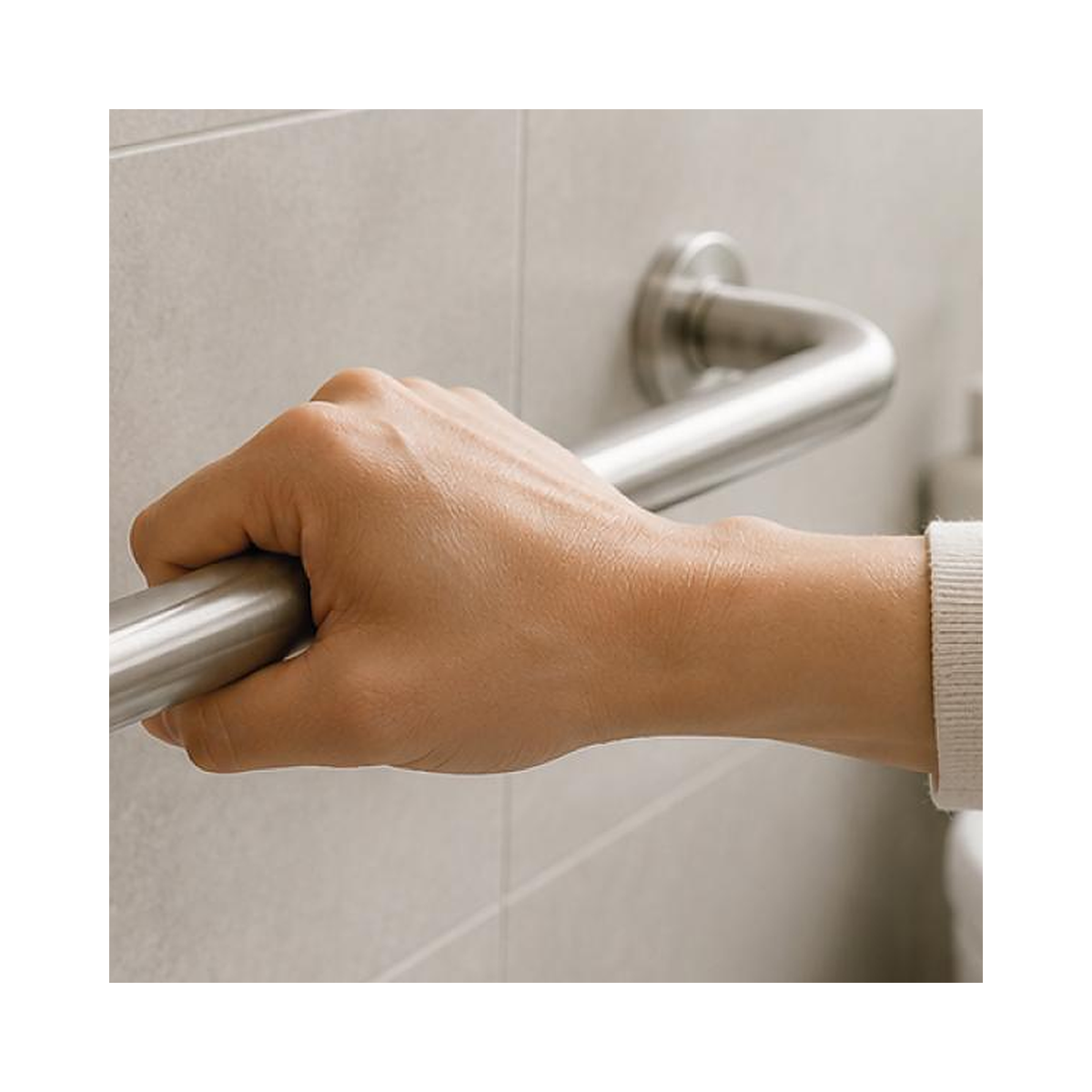 Mano tomando una barra de acero instalada en horizontal en el muro del baño